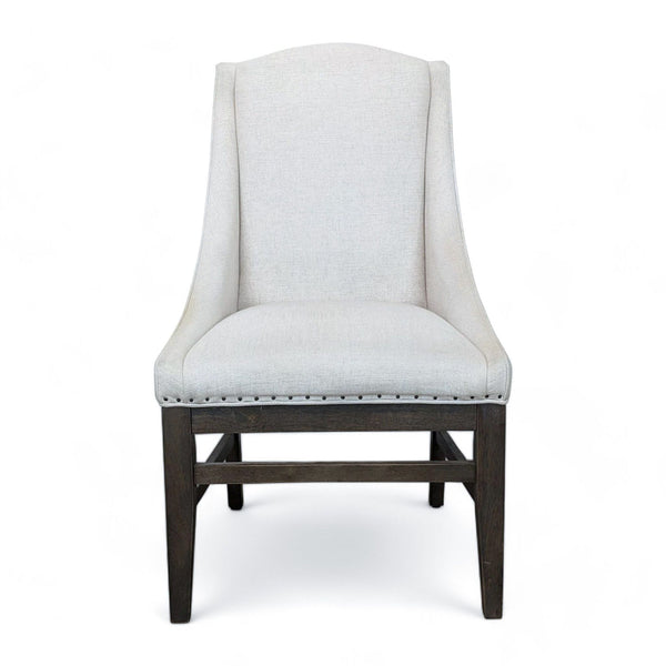 1. Front view of Tyndall Dining Chair by Universal Furniture with light fabric upholstery and nail head trim on dark tapered legs.