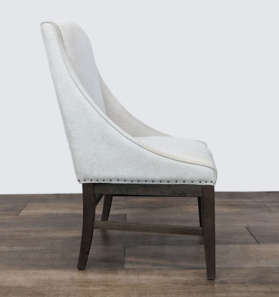 2. Side angle of the Tyndall Dining Chair showcasing the chair's gentle curve and elegant nail head detailing along the base.