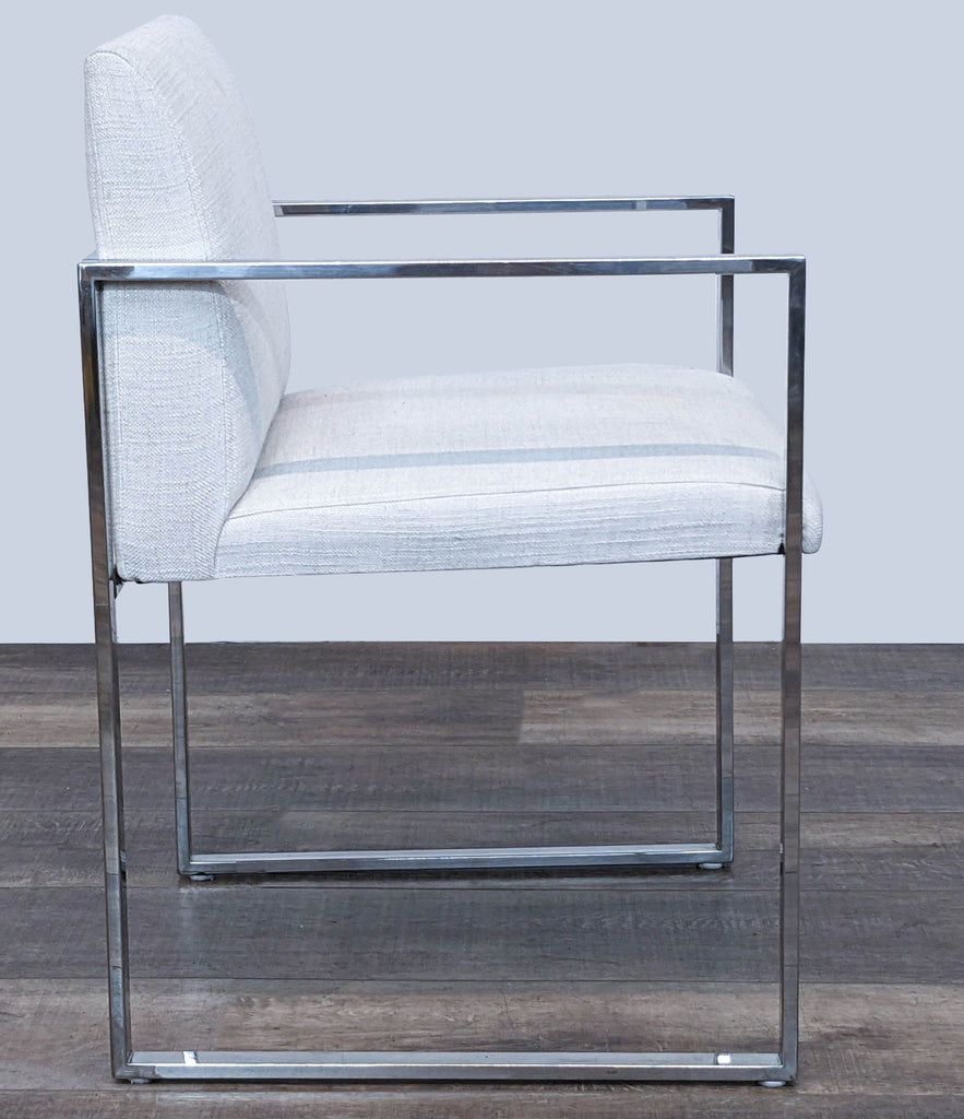Side angle view of a Reperch lounge chair featuring a sleek stainless steel frame and ivory linen seat.