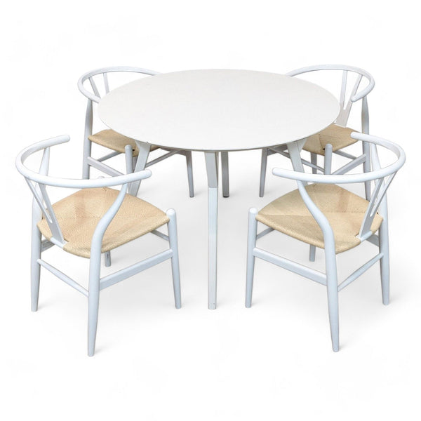 1. West Elm Mid-century round dining table with four angled Birch Lane Wyn chairs with woven seats on a white background.