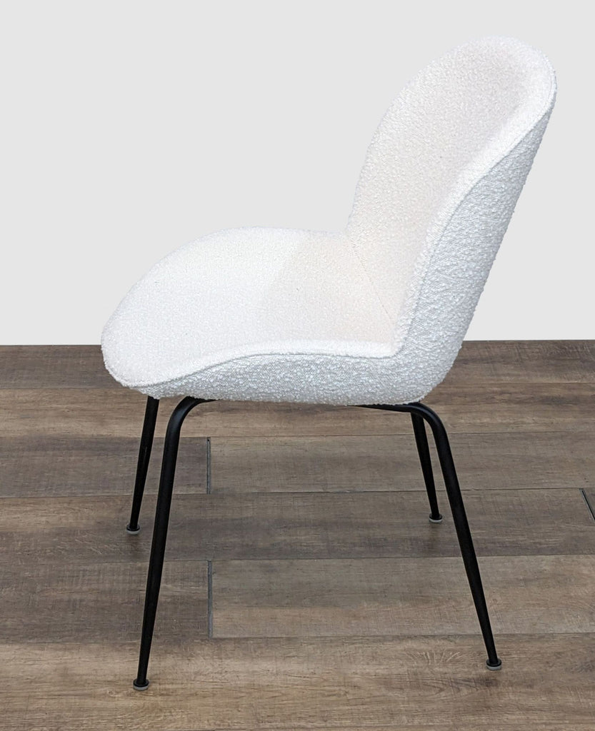 2. Side view of a plush Latese dining chair by Corrigan Studio with black legs and a curved, upholstered ivory seat.