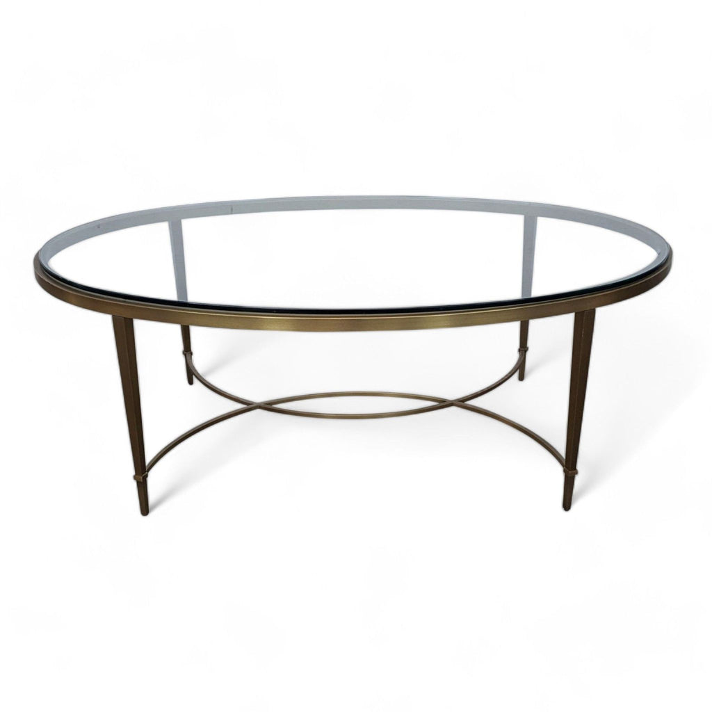 1. Oval glass-top coffee table with an antique brass base by Thomas Pheasant, showcasing a simple yet elegant design.