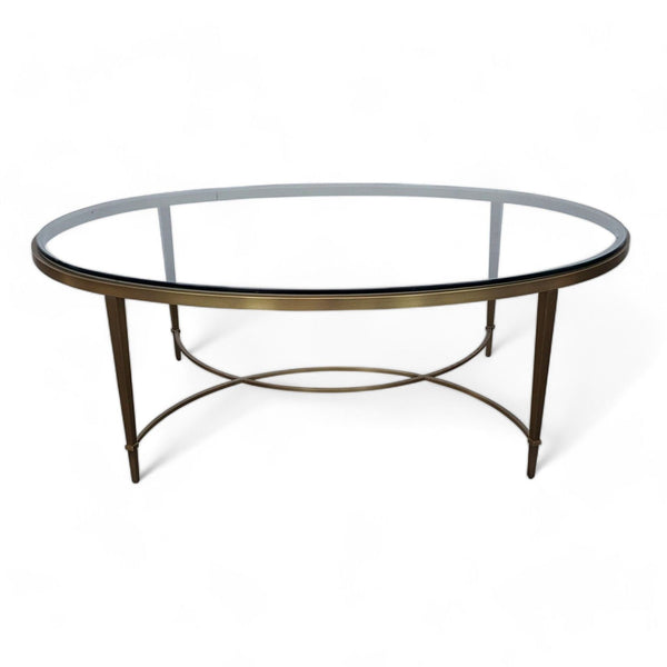 1. Oval glass-top coffee table with an antique brass base by Thomas Pheasant, showcasing a simple yet elegant design.