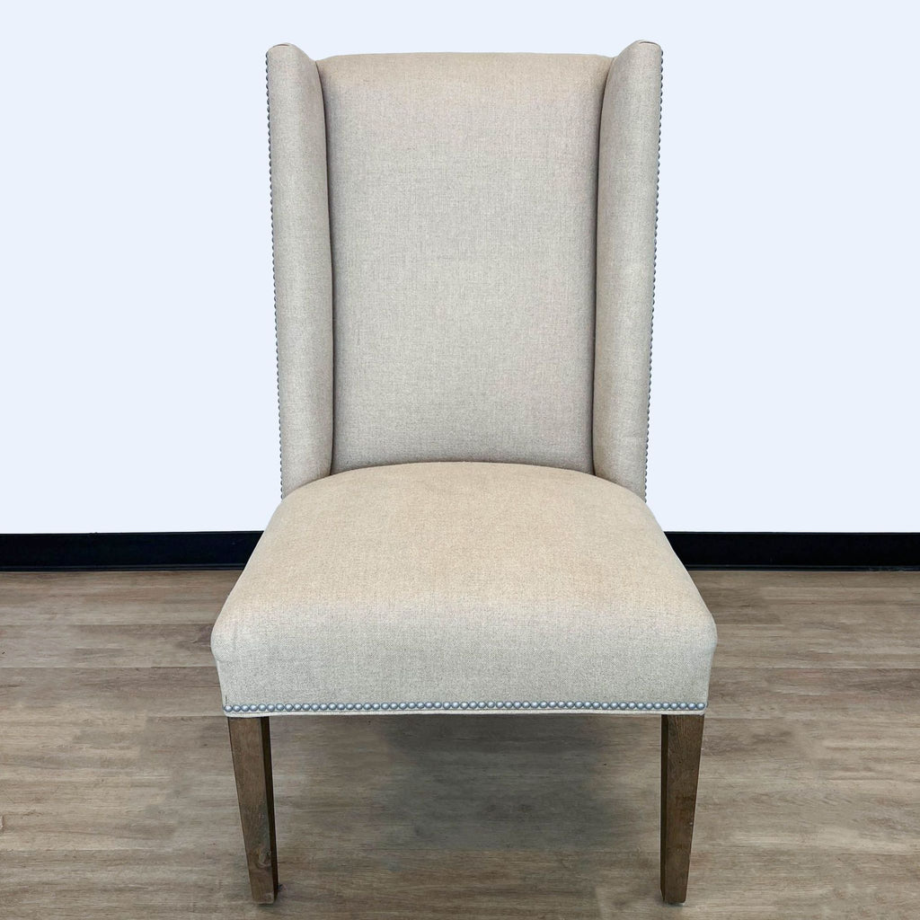 1. Reperch high-backed chair with neutral fabric and nailhead trim, sturdy wooden legs, on a hardwood floor.