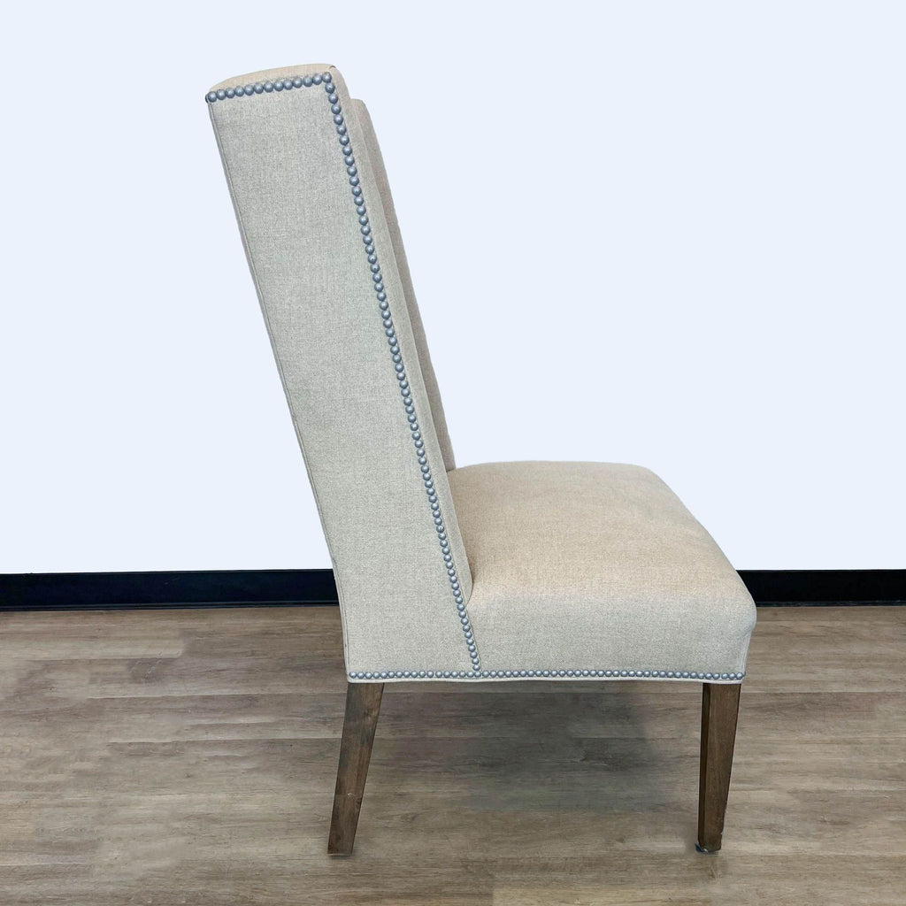 2. Side view of a Reperch lounge chair featuring nailhead detailing and a tall backrest, against a neutral wall.