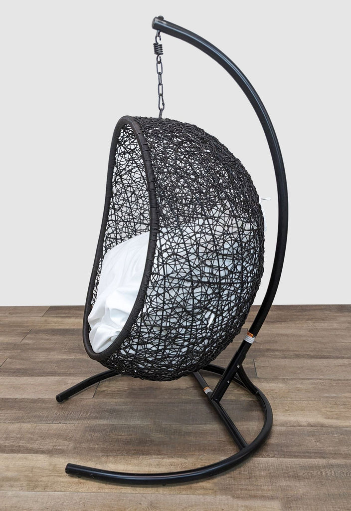Modern black wicker lounge chair, free-floating with a chain, ideal for stylish relaxation.