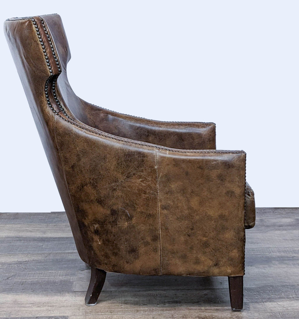 Side view of the Four Hands leather chair showcasing the high back design and nailhead detail on distressed leather.