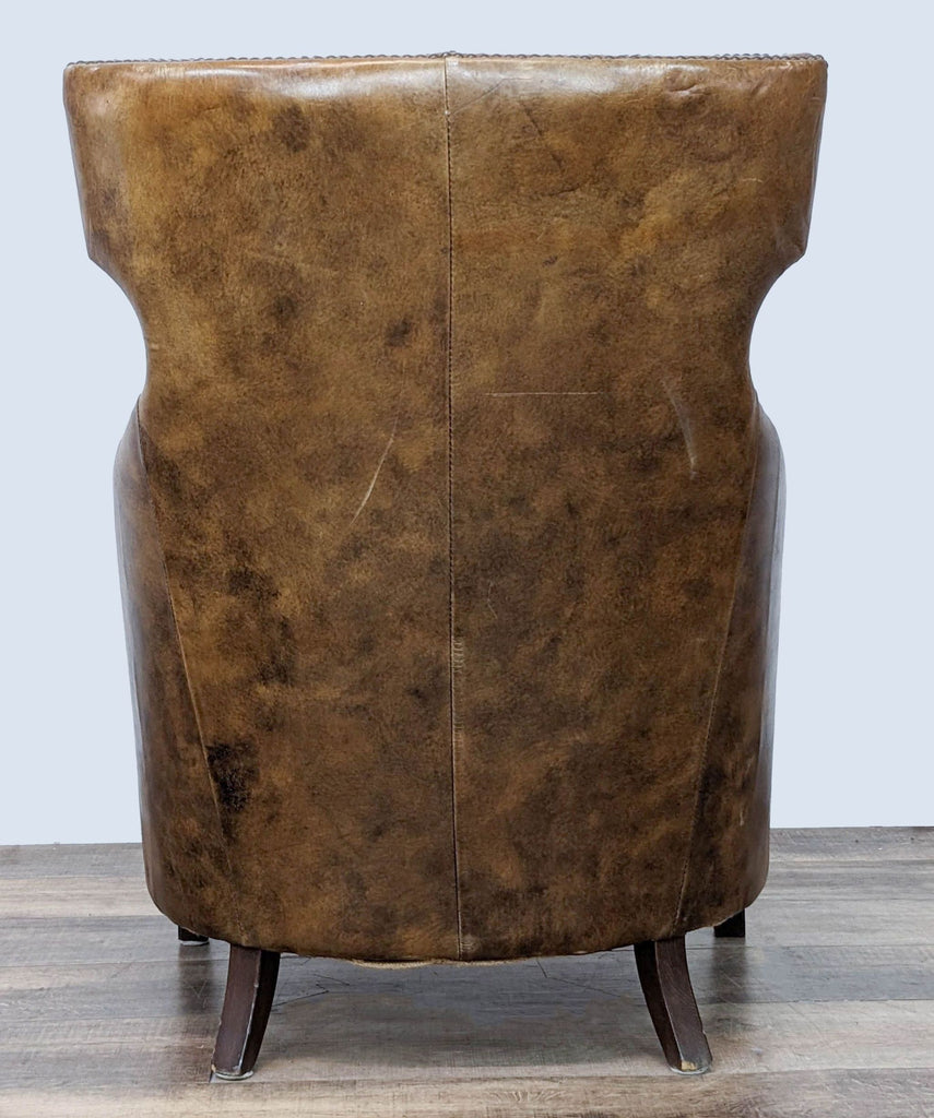 Rear view of the Four Hands high-back leather accent chair with visible wood legs and rich, textured leather upholstery.