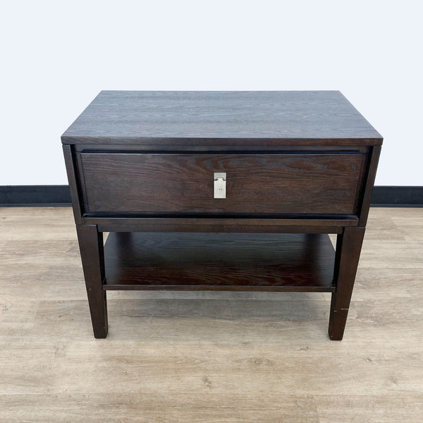 West Elm end table with a closed drawer, dark finish, on a light wood floor against a grey wall.