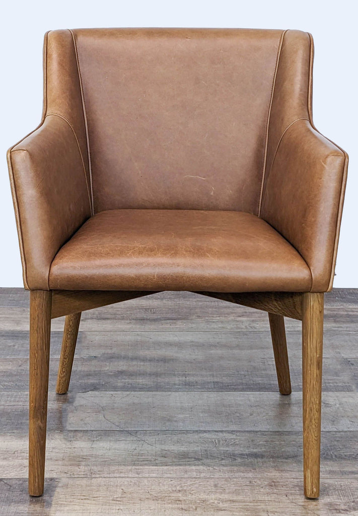 Brown leather lounge chair with sleek design and wooden legs, viewed from the front.