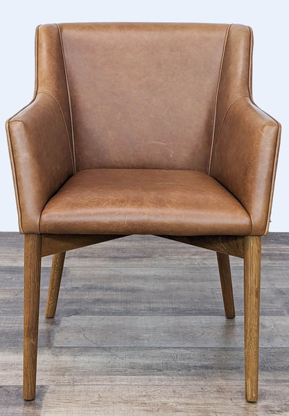 Brown leather lounge chair with sleek design and wooden legs, viewed from the front.