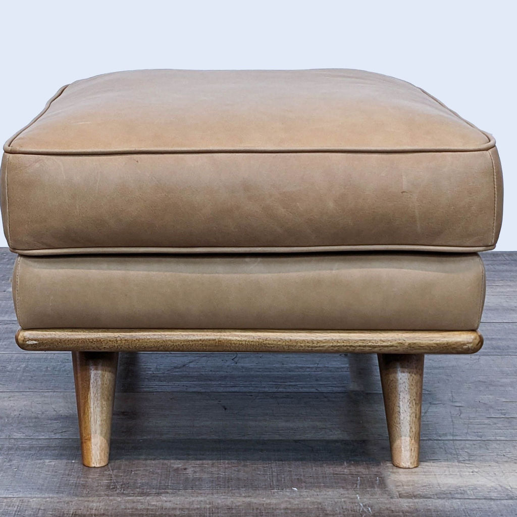 Front view of Mid-Century modern leather ottoman with solid legs.