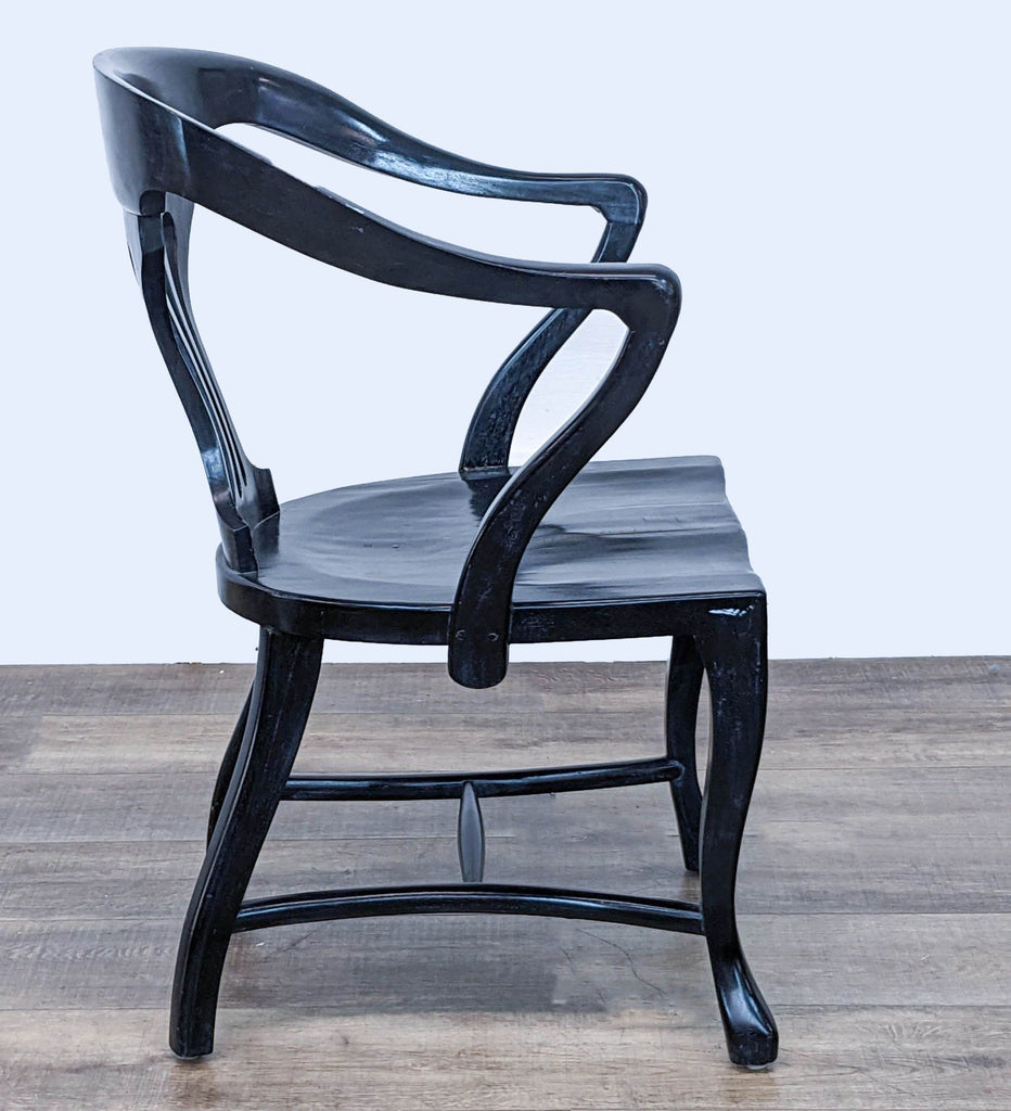 Black lacquered chair by Reperch with distinctive curved design, viewed from an angled side perspective.