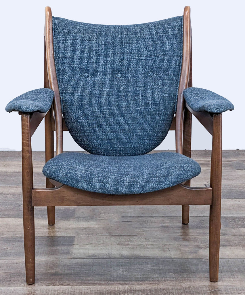 1. Front view of McCreary Modern lounge chair with blue fabric and contoured wooden frame on a wood floor background.