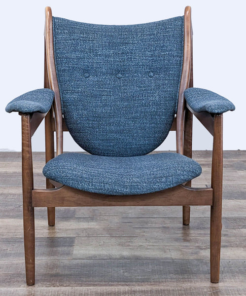 1. Front view of McCreary Modern lounge chair with blue fabric and contoured wooden frame on a wood floor background.