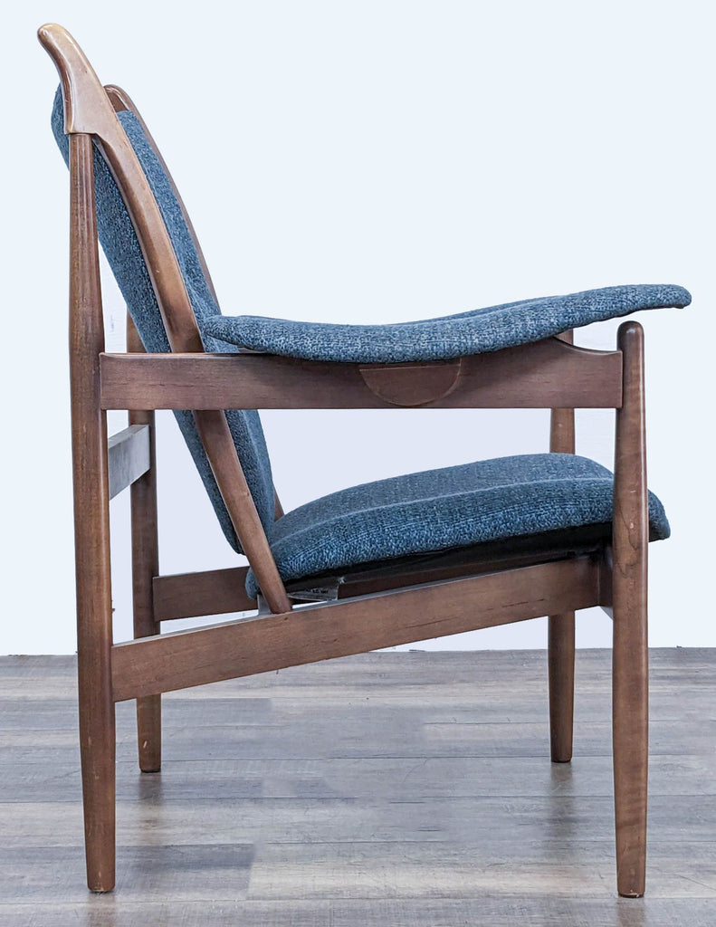2. Side angle of McCreary Modern lounge chair showcasing its curved wooden arms and angled backrest with blue upholstery.