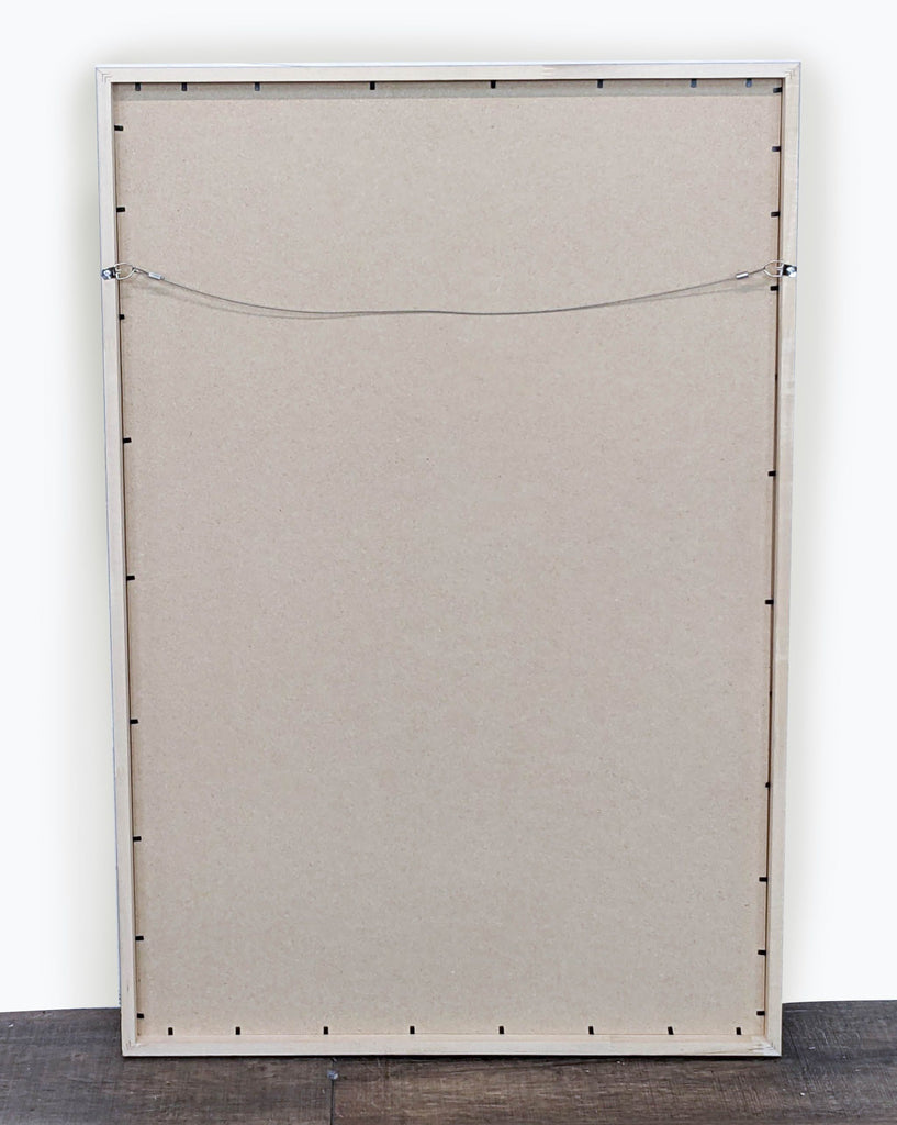 Back view of a framed landscape print with hanging wire.