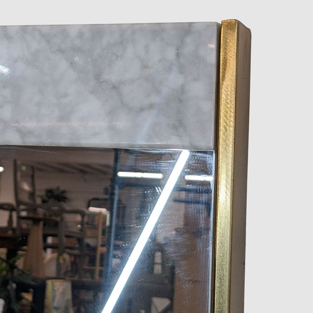 Close-up of West Elm mirror corner, highlighting the marble accent and gold finish frame detail.