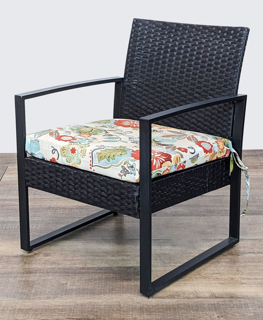 Reperch brand black resin wicker chair with floral seat cushion, side view.
