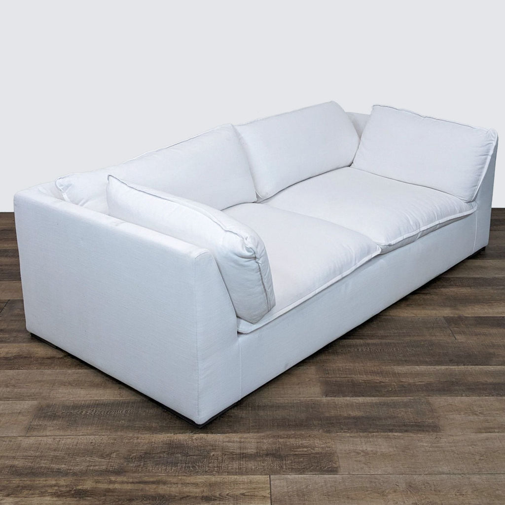 2. Italian-made Costera sofa by Restoration Hardware, a 3-seater in white fabric, displaying its clean lines and relaxed cushions on a wooden floor.
