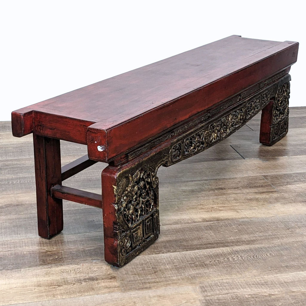 2. "Side view of Madera Home's unique opium bench, showcasing detailed golden carvings and sturdy wooden construction on a wooden floor."