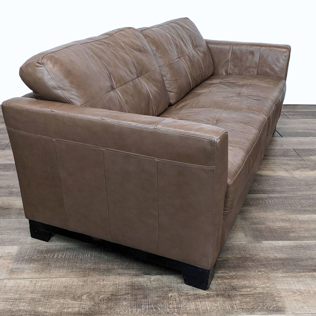 Brown leather loveseat by Chateau d'Ax, showing side angle and curved armrest.