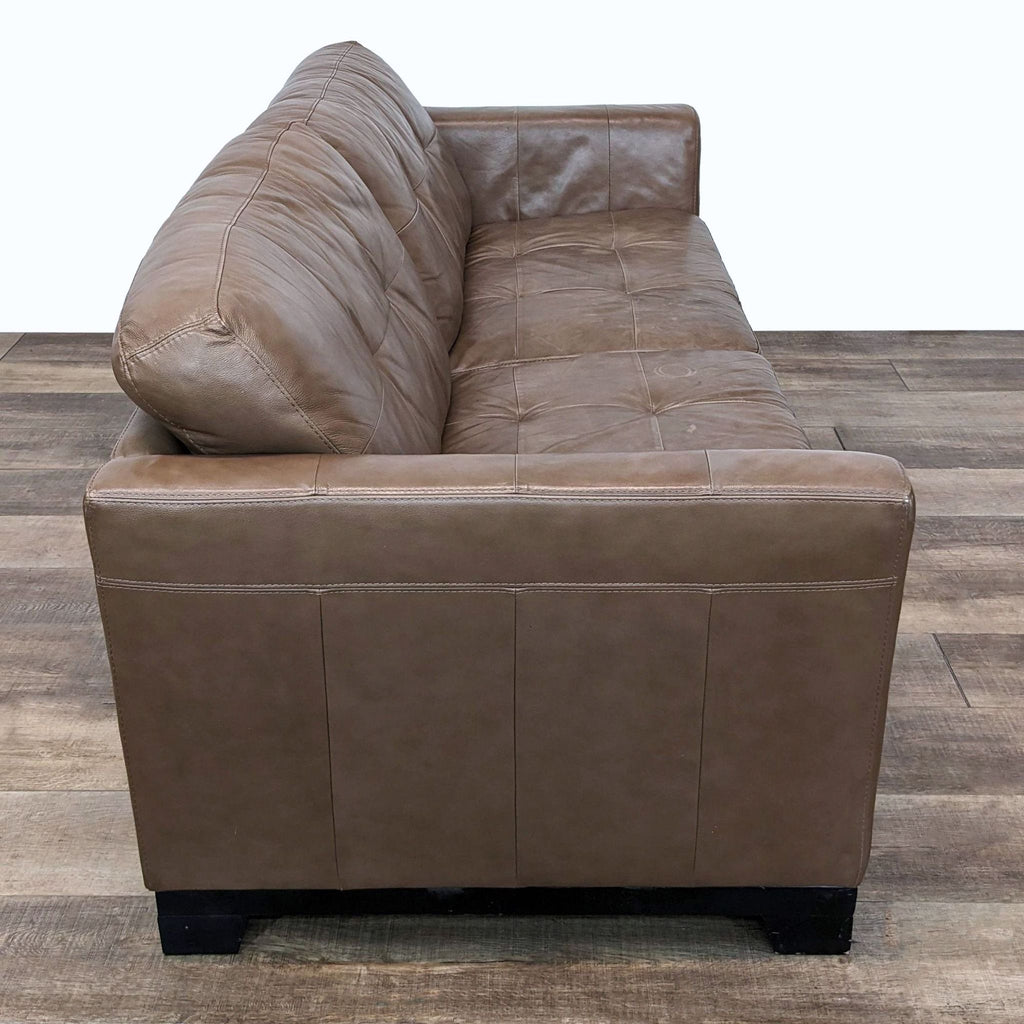 Rear view of a Chateau d'Ax brown leather loveseat with visible stitching and wood feet.