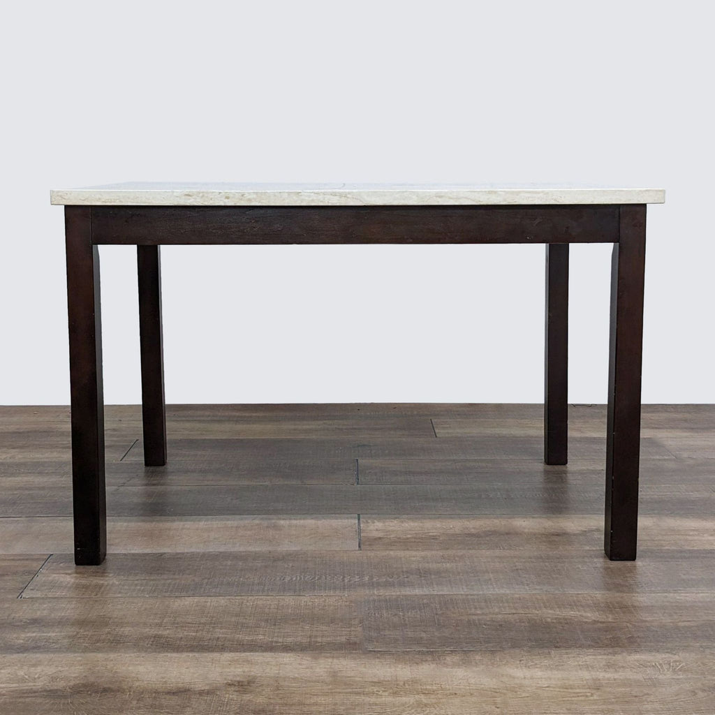 A Reperch dining table featuring a light stone top and brown wooden legs, presented in a room.