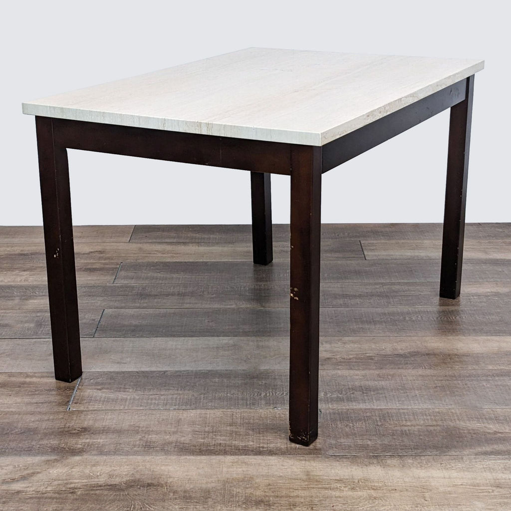 Square dining table by Reperch with a stone surface and wooden legs shown on a wooden floor.
