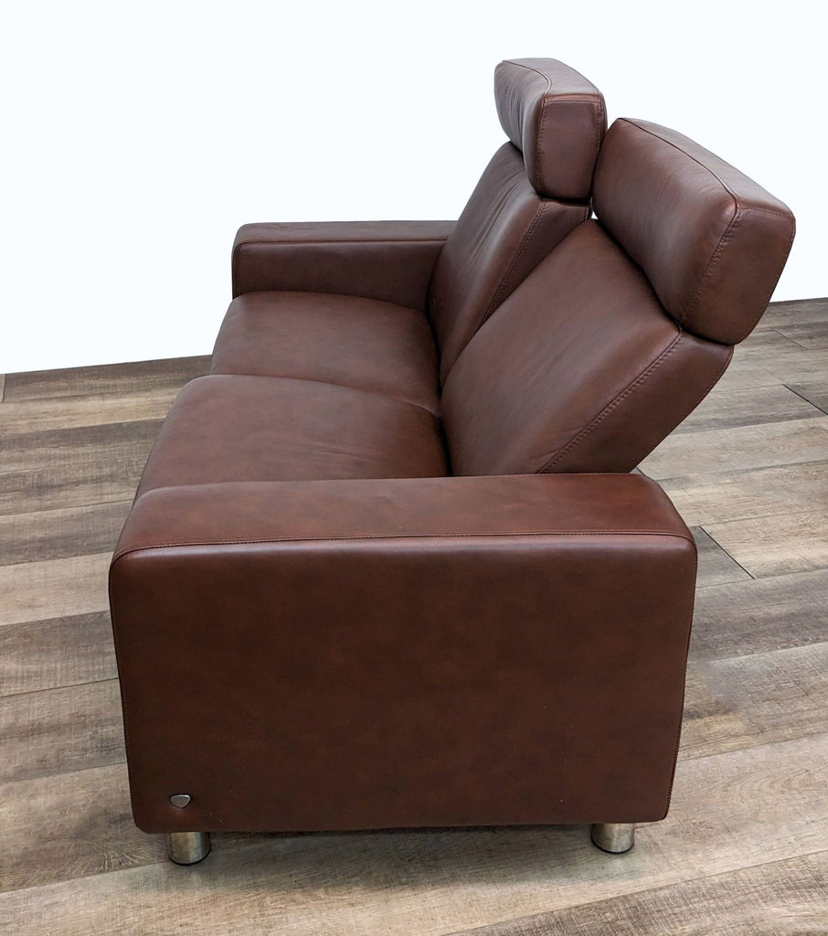 2. Side view showing the reclined back of a Stressless leather loveseat with visible metal legs.