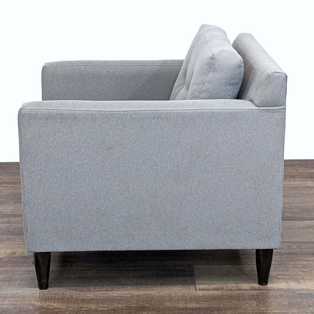 Profile of a stylish grey armchair, highlighting the cushioned back and elegant design.