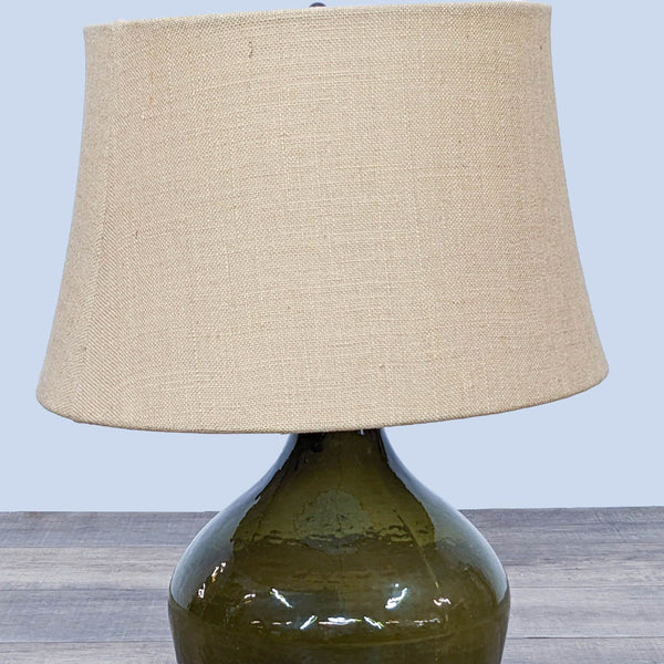 1. Olive green, mid-century style Pottery Barn table lamp with a textured burlap lampshade on a wooden surface.
