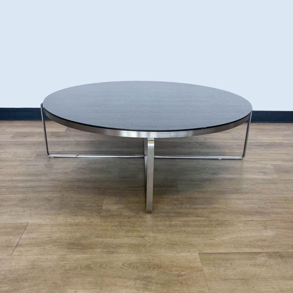 2. "Modern Reperch coffee table featuring a sturdy metal frame with cross-shaped support and a circular, textured top."