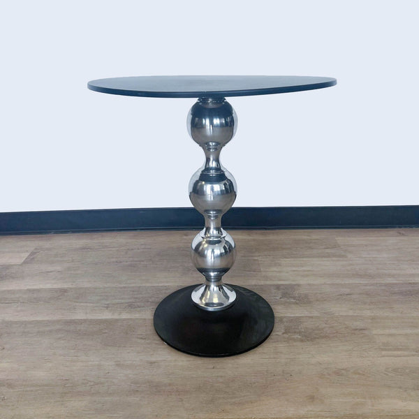 Reperch brand end table with a round black top and metallic spindle base on a wooden floor.