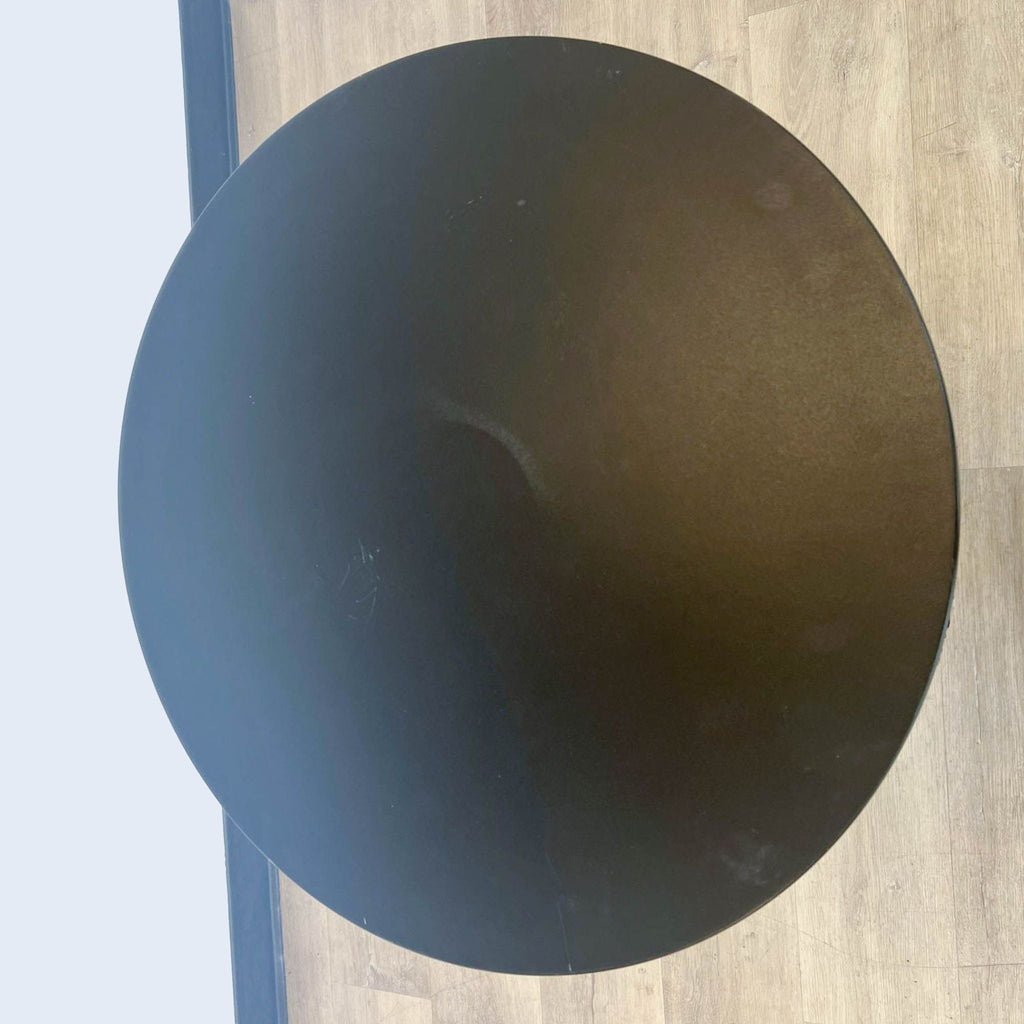 Top view of a Reperch end table showcasing the round black surface on a light wooden floor background.