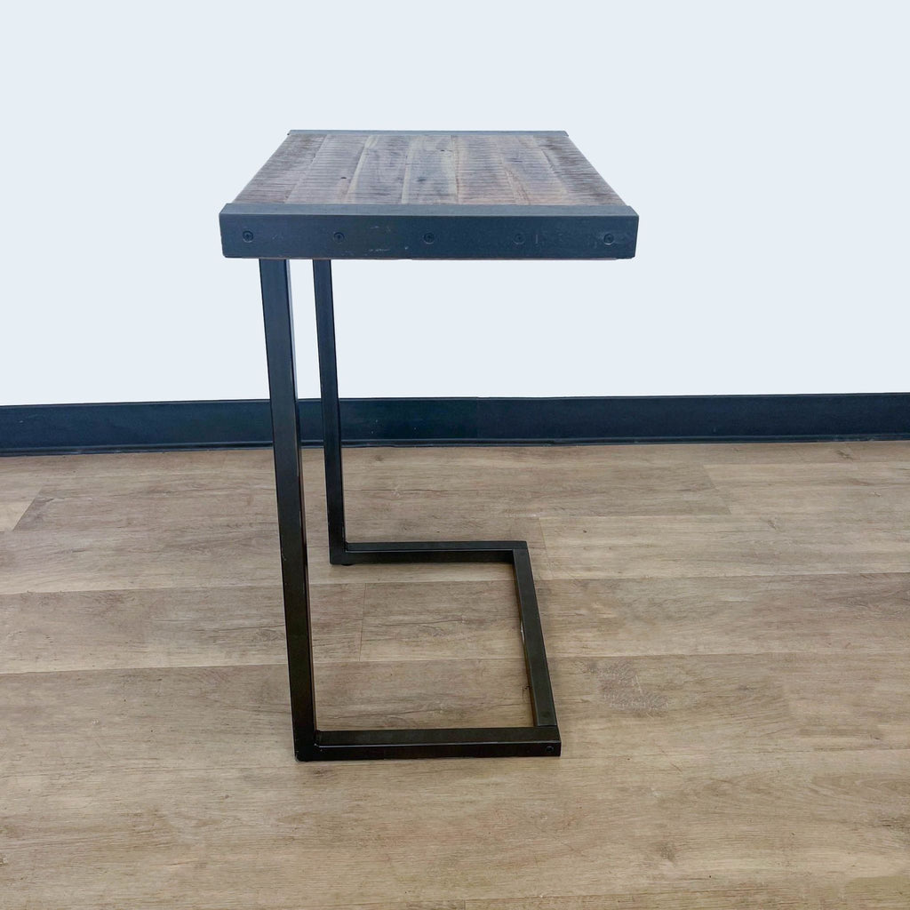 3. "Side view of a stylish wooden table with a unique black metal leg design, positioned on a laminate floor by World Market."