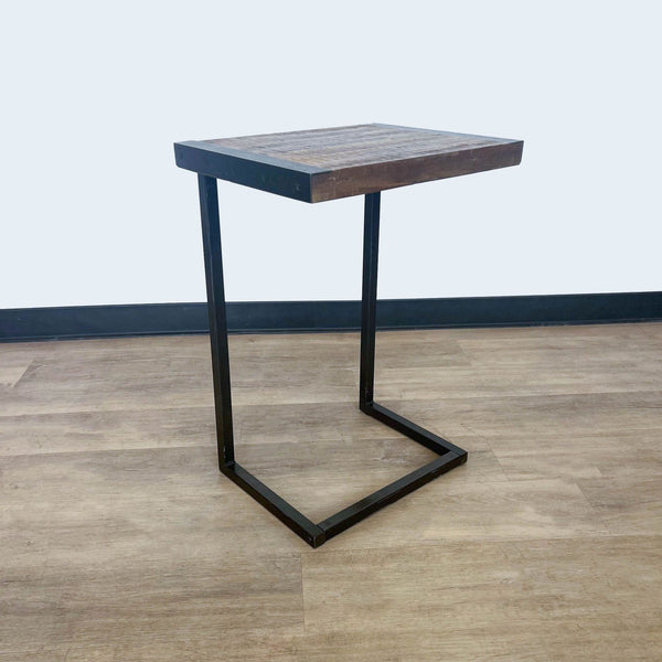 1. "Square wooden top side table with a black metal base on a wooden floor against a grey wall, World Market brand."