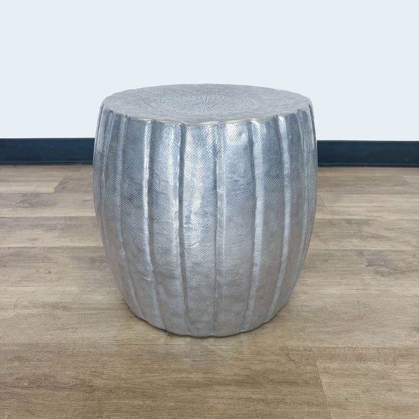 1. Viva Terra branded end table with a metallic finish and embossed vertical lines, displayed on a hardwood floor.