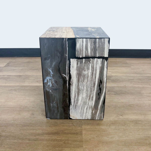 Reperch branded side table made of wood with natural and dark stained sections, against a white wall and brown floor.