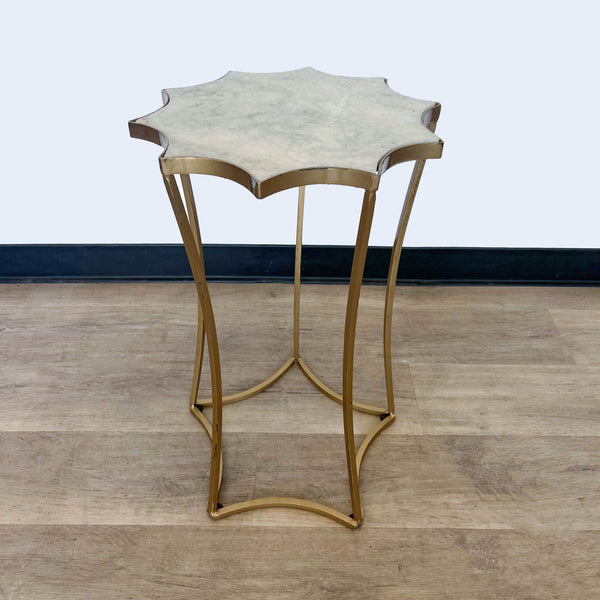 Gold-tone metal base side table with irregular top on wooden floor against plain wall by Reperch.