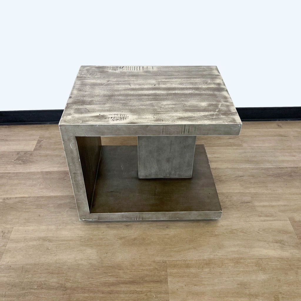Four Hands end table with a faux concrete look, in vintage gray, presented from an angled view on a wooden surface.