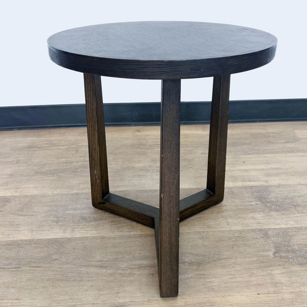 1. Reperch brand round side table with dark finish and three wooden legs on a wooden floor.
