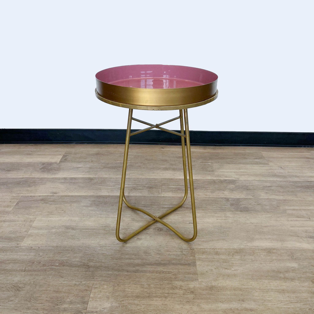 Gold side table by Reperch with round pink top and metal base.