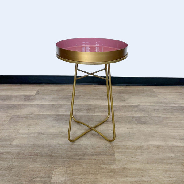 a pink glass side table with a gold base and a gold base.