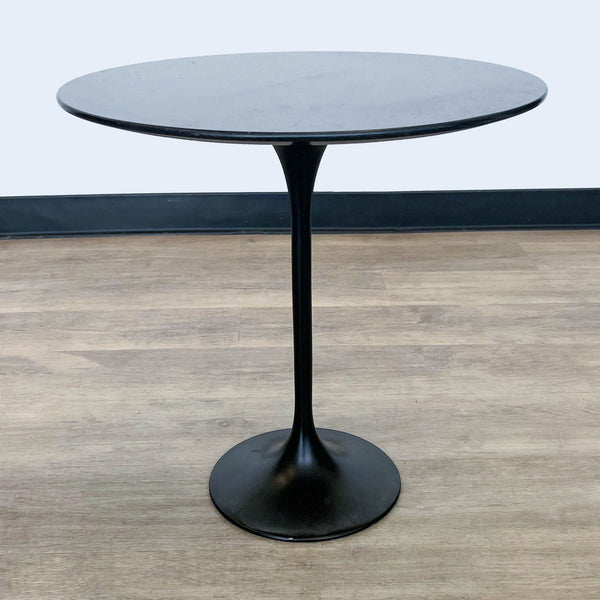 1. Reperch brand fiberglass side table with round black top and tulip base on wooden flooring.