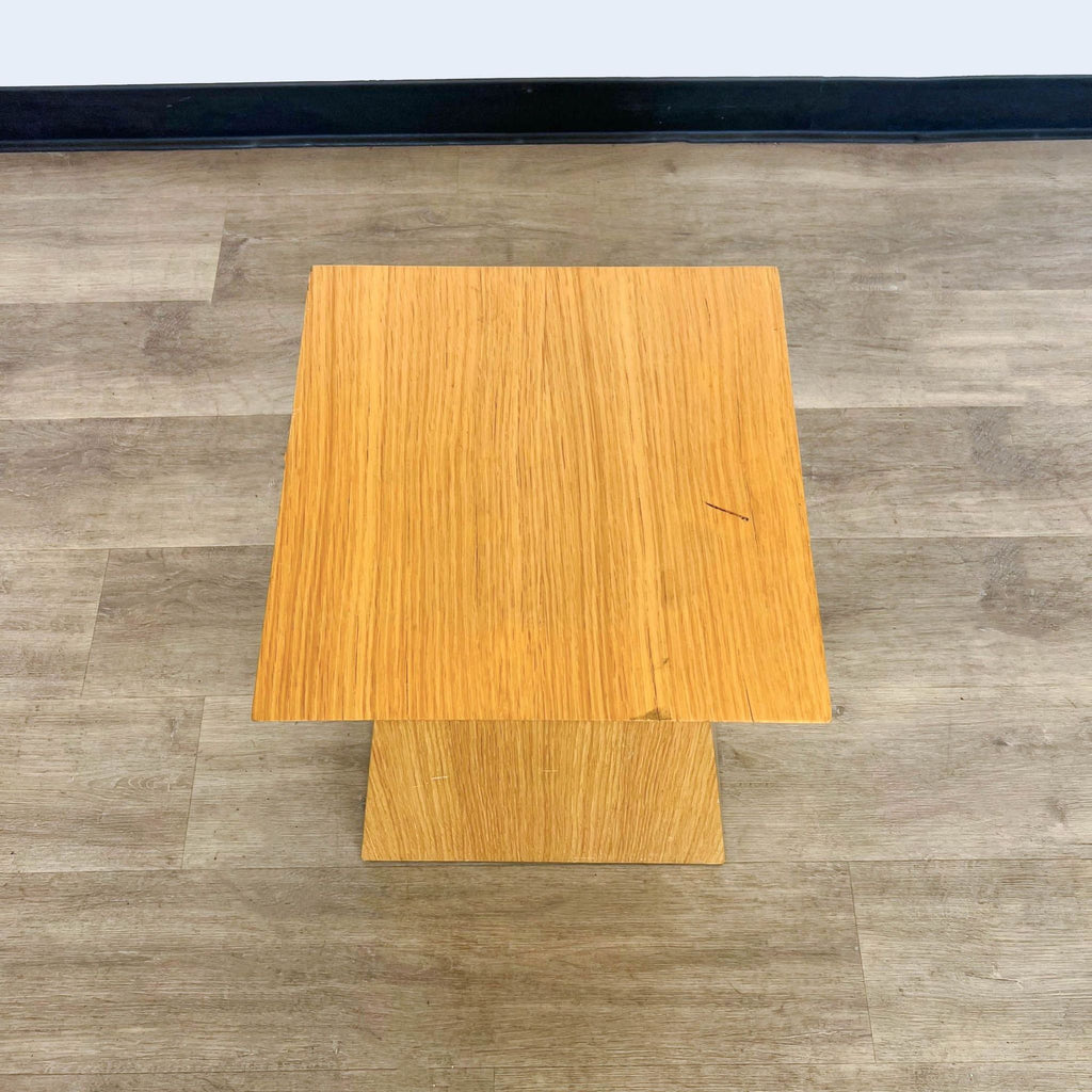 3. Top view of a square-shaped Reperch table, showcasing its wood grain texture, situated on a laminate floor.