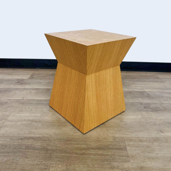 1. Reperch wooden side table with an angular, geometric design, displayed on a hardwood floor against a grey wall.