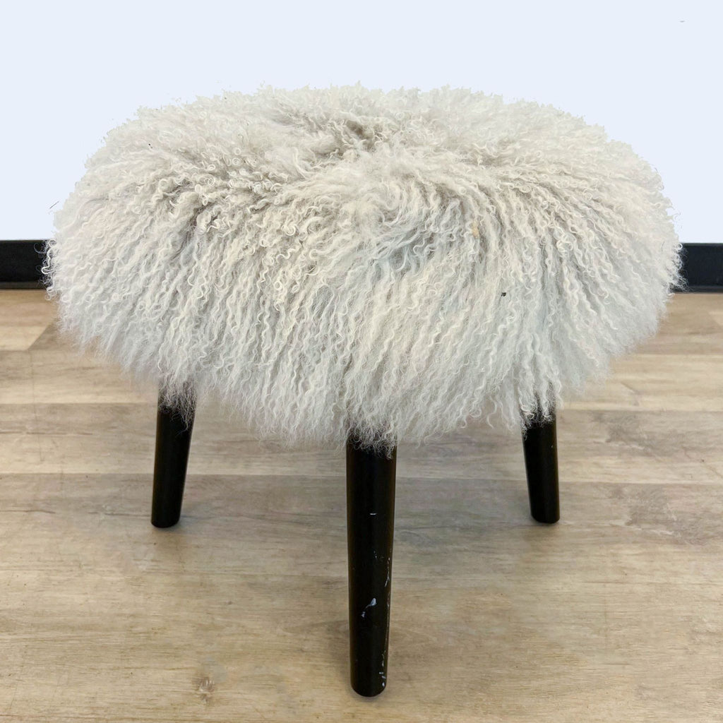 3. Rear view of a Reperch 17" shaggy stool with luxurious white fur and contrasting dark solid wood feet against a plain background.