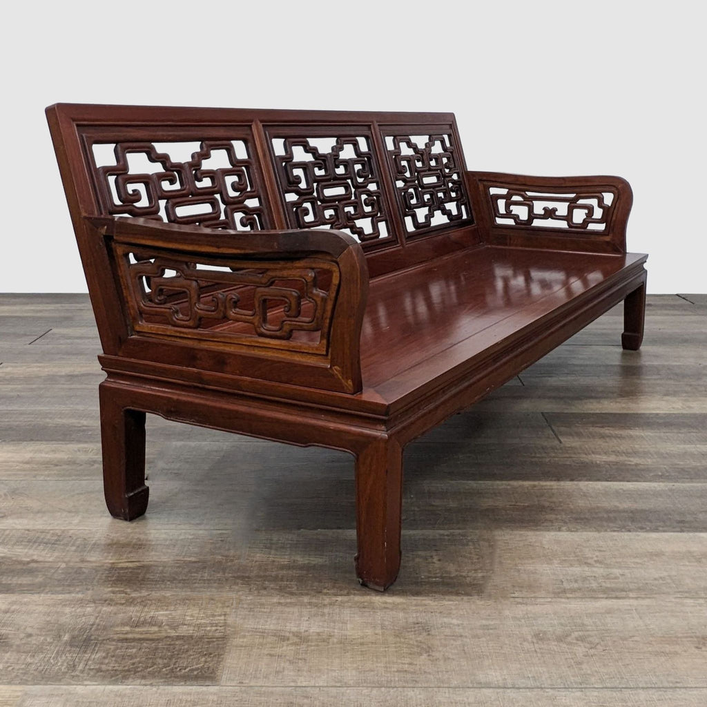 Rosewood sofa by Reperch, featuring 3-seats with intricate carvings and curved armrests, angled view on wood floor.