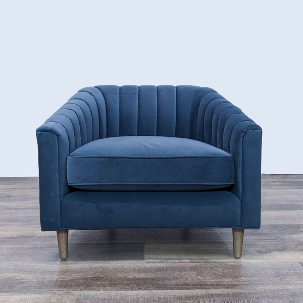 Blue velvet Four Hands lounge chair with a barrel back, channel tufting, and tapered wood legs, front view.